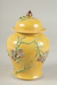 AN EARLY 20TH CENTURY CHINESE YELLOW GROUND JAR AND COVER, carved with peaches, 20cm high.