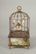A SMALL NOVELTY SINGING BIRD in a cage. 6ins high.