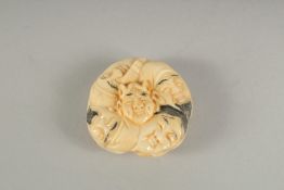 A CARVED BONE CIRCULAR FACES NETSUKE.