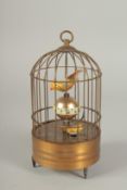 A SMALL NOVELTY SINGING BIRD in a cage. 7.5ins high.