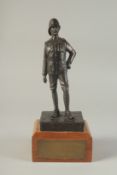 A SPELTER FIGURE OF A SOLDIER on a wooden base. 9ins high.