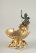 A BRONZE AND GILT BRONZE TABLE SALT modelled as a cherub, seated on a shell shaped dish. 7ins high.