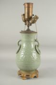 A CHINESE CELEDON PORCELAIN LAMP with ring handles, converted to electricity, on a gilt metal base.