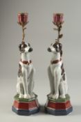 A PAIR OF PORCELAIN AND ORMOLU CANDLESTICKS modelled as seated dogs. 13ins high.