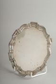 A SMALL PIE CRUST SILVER SALVER on three knurled feet. 7ins diameter. Birmingham 1931. Weight: