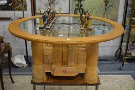 A highly unusual oak chess table, the framed circular glass top supported on a base in the form of a