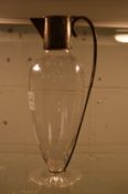 A plain glass claret jug of tapering form with silver mounts.