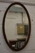 A mahogany framed oval wall mirror and a Victorian walnut over-mantel mirror.