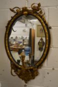 A 19th century gilded and ebonised oval girandole mirror (faults).