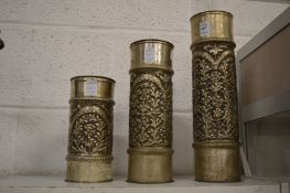 A graduated set of three embossed white metal candle stands.