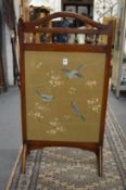A mahogany framed fire screen with embroidered panel depicting birds on a branch (glass cracked).