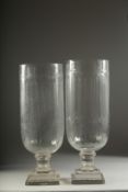 A PAIR OF CUT GLASS HURRICANE LAMPS on square bases. 16ins high.