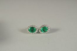 A PAIR OF 18CT WHITE GOLD. DIAMOND AND EMERALD EAR STUDS.