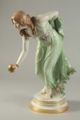 A MEISSEN PORCELAIN GIRL PLAYING BOWLS, modelled by W. SCHOTT, on a circular base. Cross swords mark