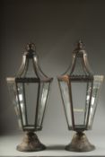 A PAIR OF COPPER METAL GLAZED LANTERNS on circular bases. 27ins high.