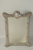 A GOOD LARGE VICTORIAN SILVER REPOUSSE DECORATED EASEL MIRROR, Chester 1901. 20ins x 14ins.