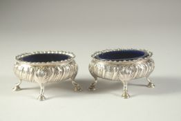 A PAIR OF GEORGE III SILVER OVAL SALT CELLARS with sapphire blue liners on four pad feet. London