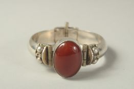 A SILVER BANGLE set with a Cornelian stone.