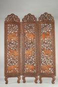 AN INDIAN OR THAI CARVED AND PIERCED WOODEN THREE-PANEL FOLDING SCREEN, carved with foliate panels