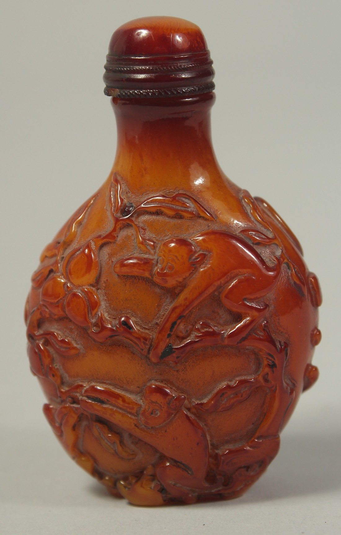 A CHINESE AMBER STYLE SNUFF BOTTLE, decorated with peaches and monkeys and bearing four character
