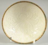 A CHINESE DING STYLE TEA BOWL, with carved floral decoration and gilt rim, 10cm diameter.