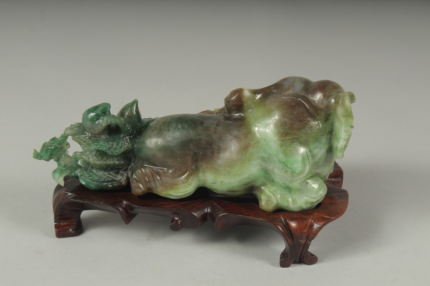 A CHINESE CARVED JADE FIGURE OF AN ELEPHANT ON A FITTED CARVED HARDWOOD STAND, figure 14cm long. - Image 2 of 4