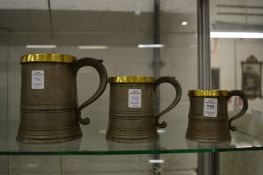 Graduated set of three brass bound pewter tankards, quart, pint, half pint.