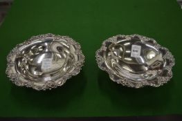 A pair of sterling silver pedestal dishes with decorative rims.