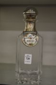 A cut glass whiskey decanter with white metal mount and stopper together with a porcelain whiskey