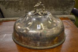 A large plated meat dome with ornate handle.