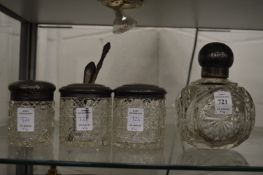 Cut glass perfume bottle with enamel decorated silver top together with three silver topped dressing