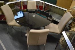 A stylish smoked glass and chrome circular pedestal dining table with four chairs.