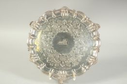 A VICTORIAN SILVER PIE CRUST SALVER with shell border on three curving feet, 8.75ins diameter.