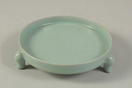 A CHINESE CELADON GLAZED RU WARE TRIPOD CIRCULAR STAND. 15cms diameter.