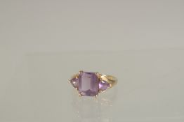 A GOLD THREE STONE AMETHYST RING.