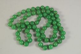 A STRING OF JADE BEADS, 84cms long.