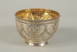 A VICTORIAN SILVER CIRCULAR BOWL repousse with flower and bead decoration. 4.25ins diameter.