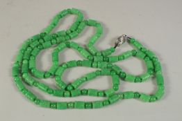 A LONG STRING OF CARVED JADE BARREL BEADS with white gold clasp. 150cms long.