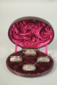 A SET OF FOUR VICTORIAN SILVER CIRCULAR SALTS AND SPOONS in a fitted case. Sheffield 1885.