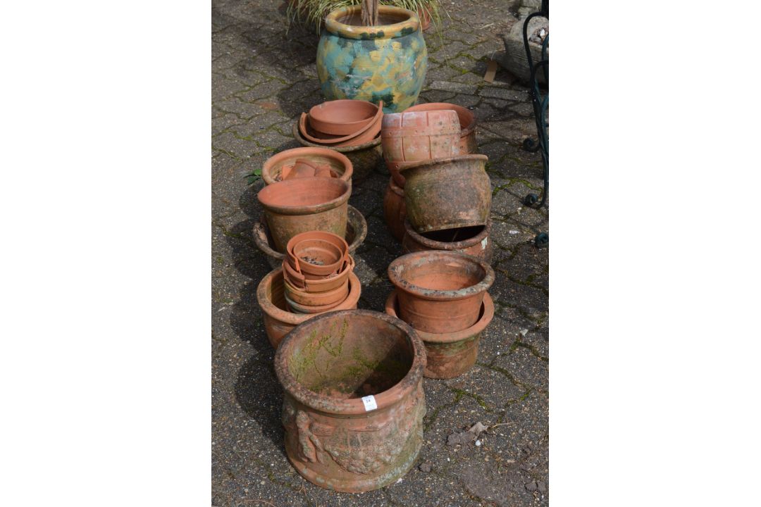 A large quantity of terracotta plant pots together with a large pot with artificial tree.