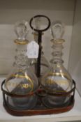 A decanter stand containing three decanters with stoppers, each with gilded decoration Hollands