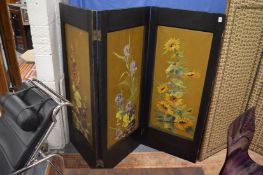 An ebonised framed three panel folding screen, each panel hand painted with floral design.