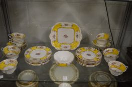 Decorative tea ware with yellow borders and floral sprays.