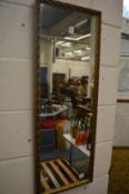 A narrow gilt framed mirror.