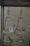 A pair of cut glass scent or oil bottles with white metal mounts.