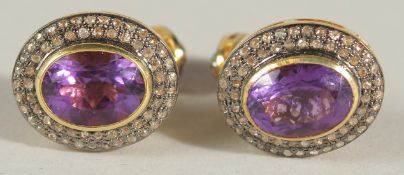 A PAIR OF CUFFLINKS IN YELLOW METAL SET WITH OVAL AMETHYSTS SURROUNDED BY R/C DIAMONDS, TOGETHER