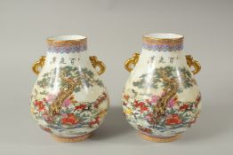 A PAIR OF CHINESE PORCELAIN TWO HANDLED VASES, deer in a landscape. 23cms high.