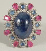 A DRESS RING SET WITH A LARGE OVAL CABOCHON BLUE SAPPHIRE SURROUNDED BY RUBIES, further sapphires