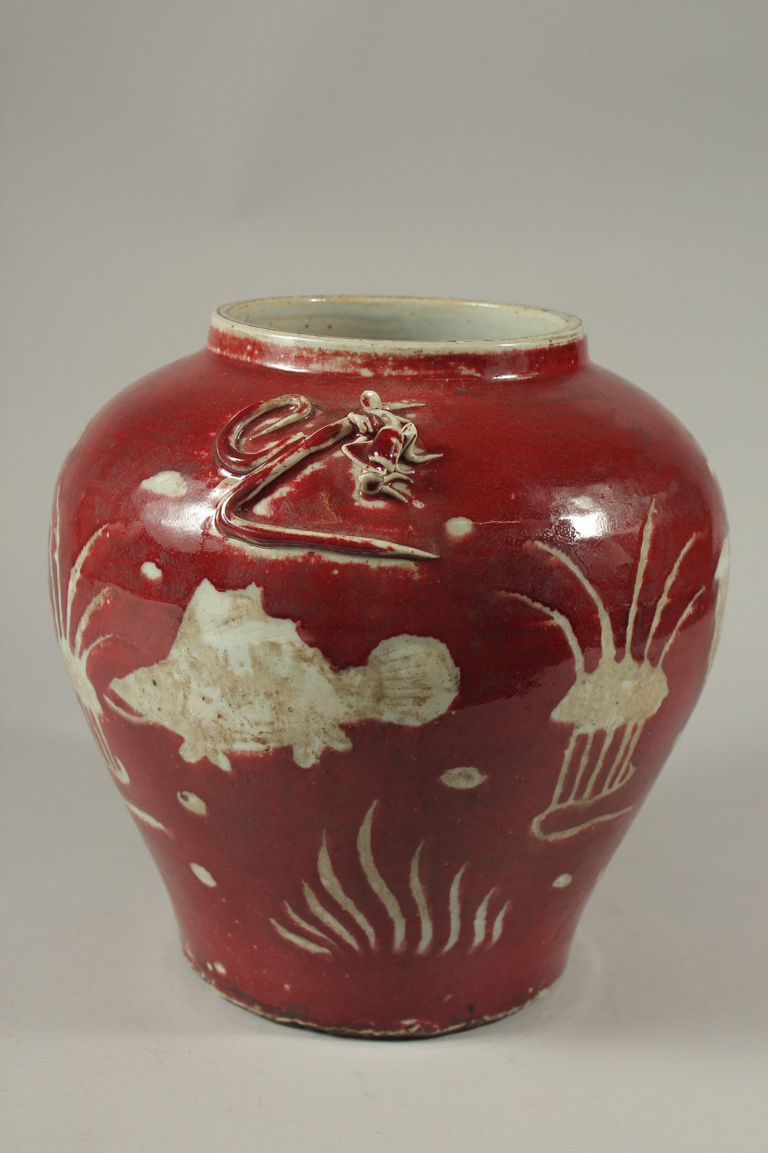 A CHINESE RED POTTERY BULBOUS VASE decorated with fish. 24cms high.