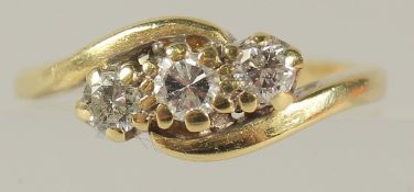 AN 18CT GOLD THREE STONE DIAMOND CROSSOVER RING.